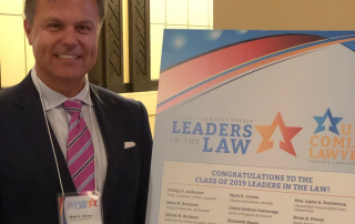 Image of Mark Groves in beside Leaders in the Law poster