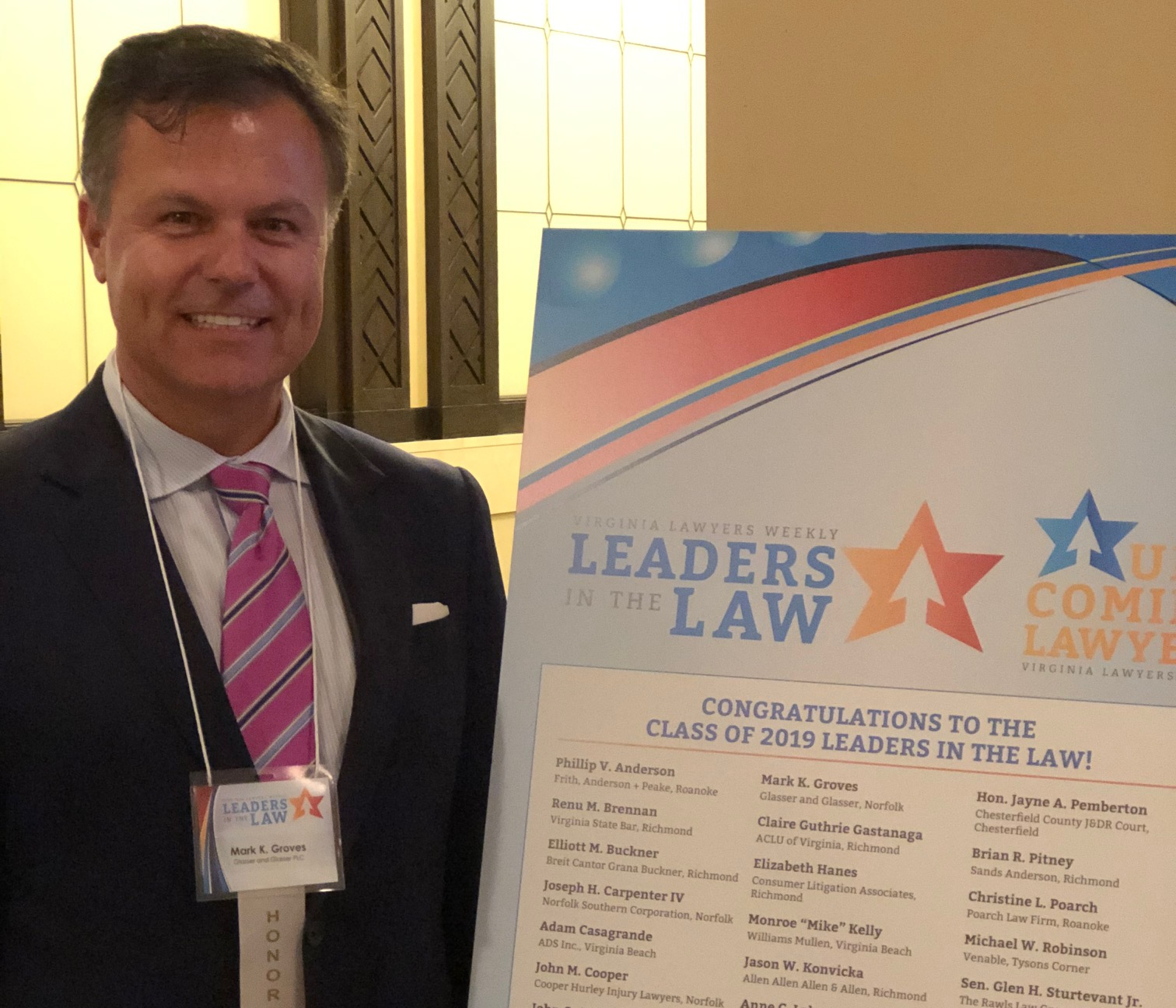 Image of Mark Groves in beside Leaders in the Law poster