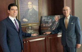 Image of Jake and Michael Glasser in front of Bernard and Richard Glassers' portrait